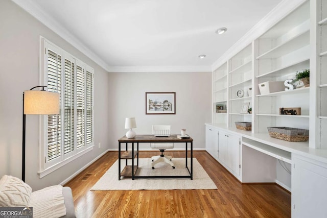 home office with built in features, crown molding, built in desk, wood finished floors, and baseboards