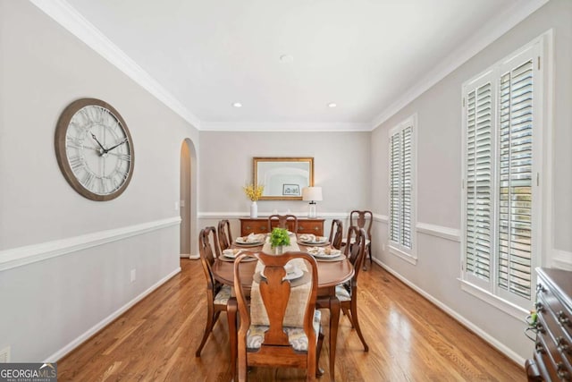 dining room with crown molding, arched walkways, and wood finished floors