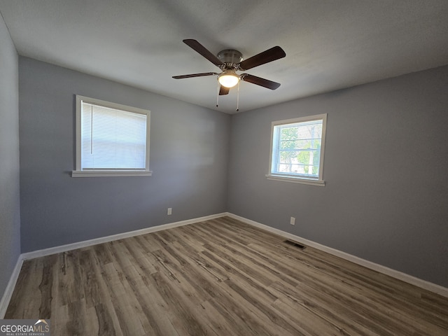 spare room with ceiling fan, wood finished floors, visible vents, and baseboards