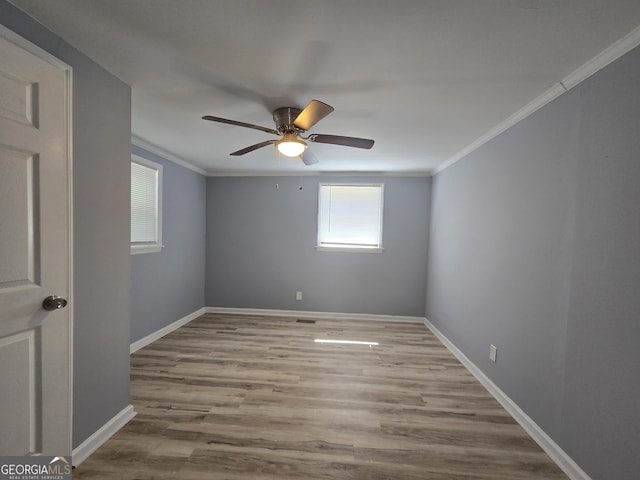 spare room with a ceiling fan, baseboards, crown molding, and wood finished floors