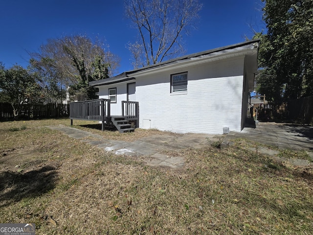 exterior space featuring a deck, brick siding, and fence