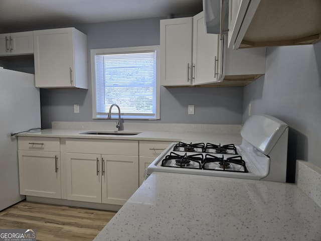 kitchen with light countertops, white appliances, white cabinets, and a sink