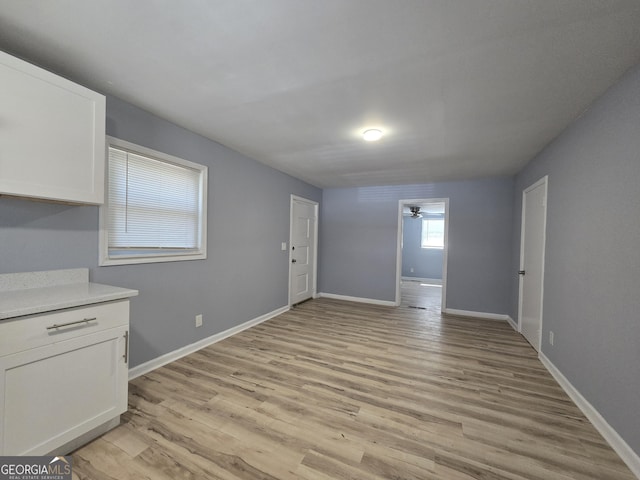 unfurnished dining area featuring a ceiling fan, light wood-style flooring, and baseboards