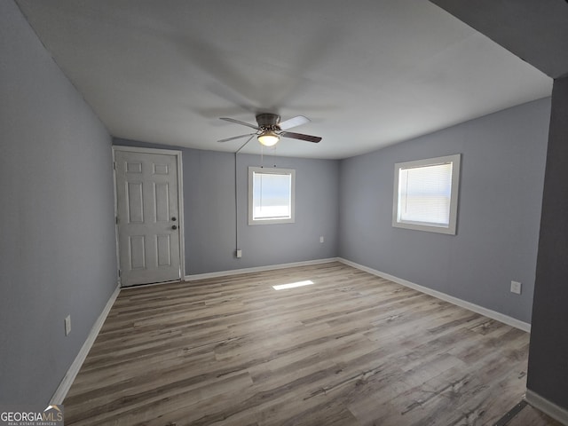 unfurnished room with wood finished floors, a ceiling fan, and baseboards