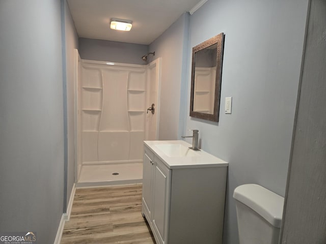 bathroom featuring vanity, a stall shower, wood finished floors, and toilet