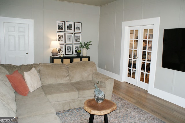 living area with wood finished floors, a decorative wall, and french doors