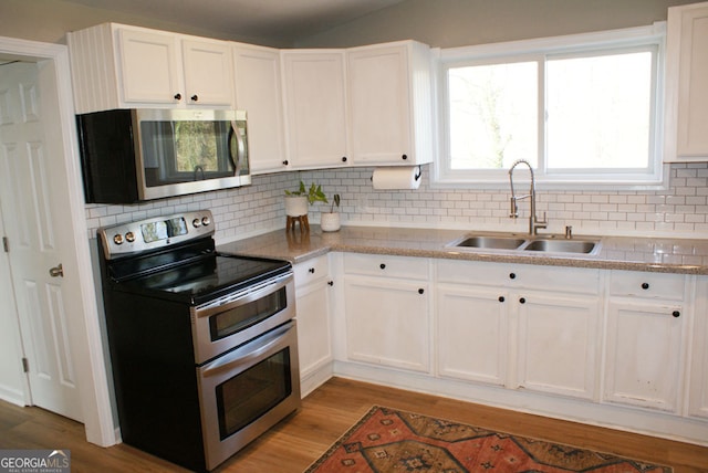 kitchen with light wood finished floors, white cabinets, appliances with stainless steel finishes, and a sink