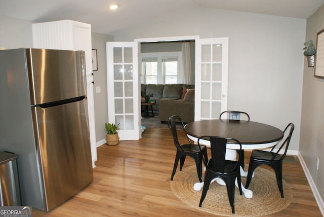 dining space with baseboards, light wood-type flooring, lofted ceiling, recessed lighting, and french doors