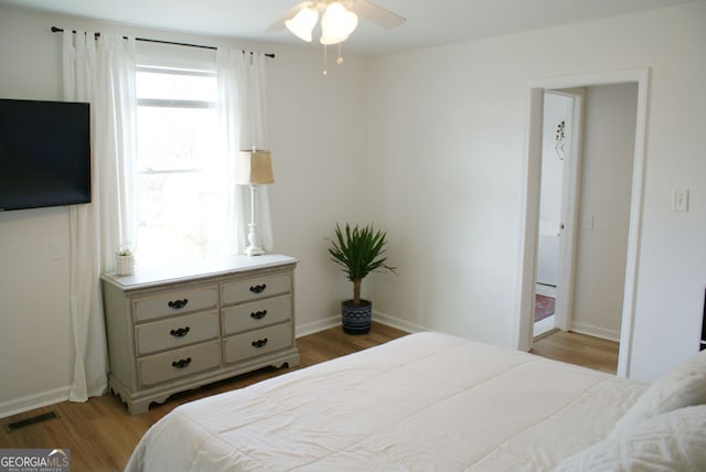 bedroom featuring visible vents, a ceiling fan, baseboards, and wood finished floors