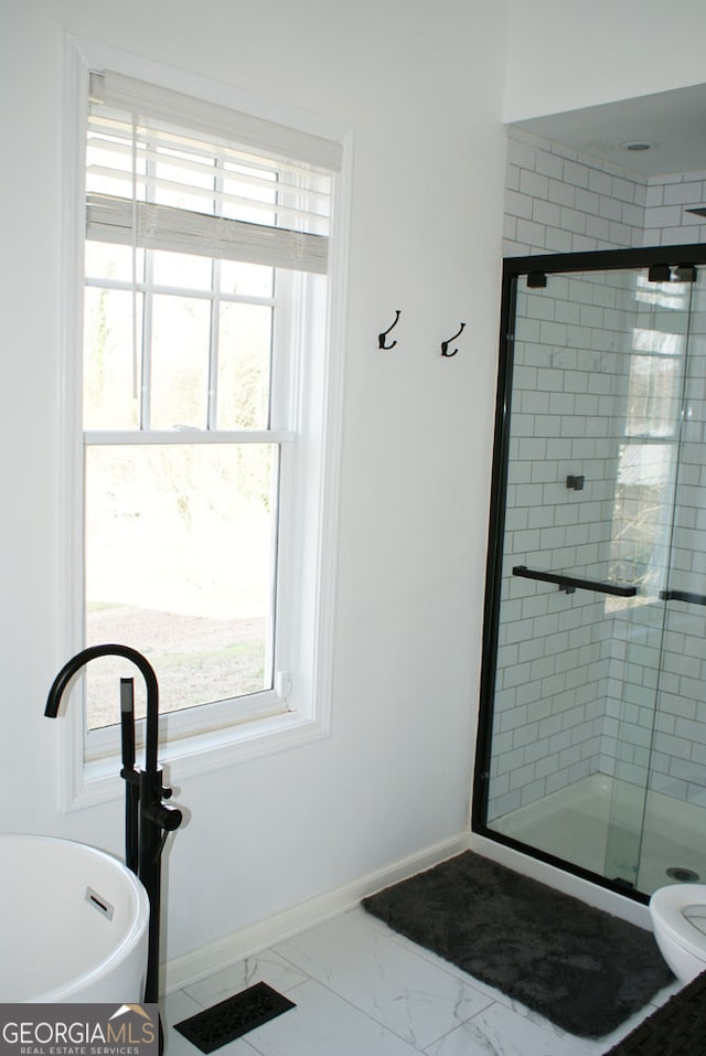 bathroom featuring marble finish floor, a stall shower, toilet, and baseboards