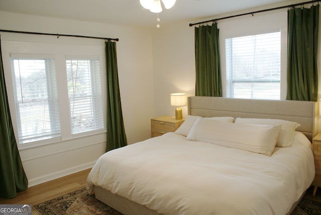 bedroom with multiple windows and wood finished floors