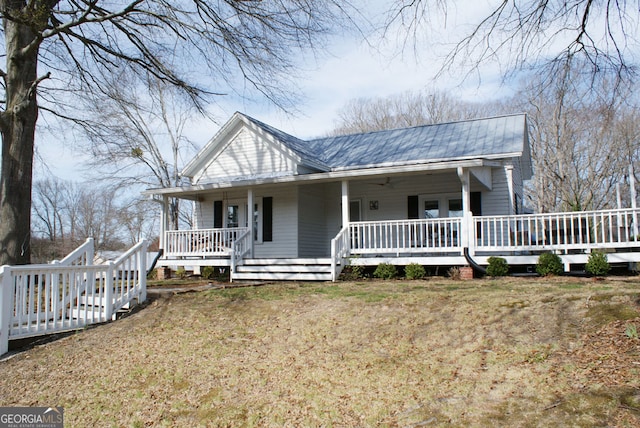 farmhouse featuring metal roof, a ceiling fan, a porch, and a front yard