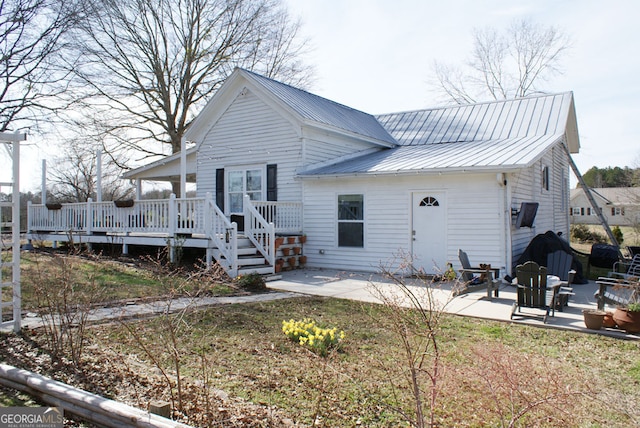 rear view of house featuring a patio area, a wooden deck, and metal roof