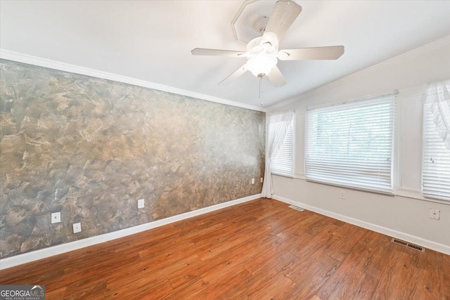 unfurnished room with visible vents, ornamental molding, a ceiling fan, wood finished floors, and baseboards