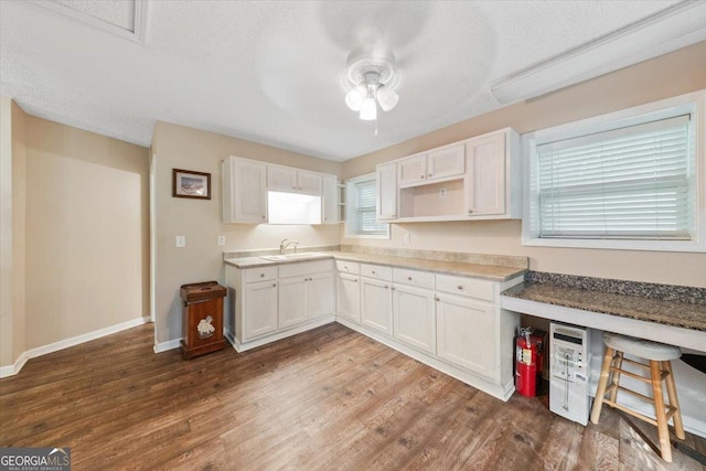 kitchen with a sink, open shelves, wood finished floors, and white cabinetry