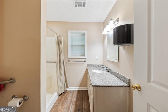 full bathroom featuring a stall shower, visible vents, vanity, and a textured ceiling