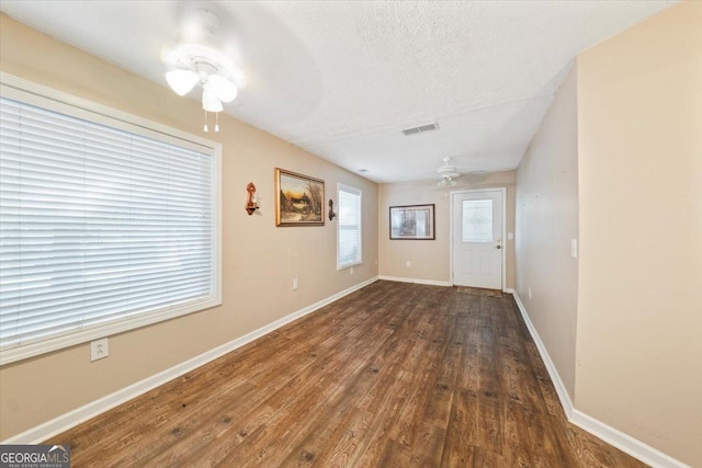 interior space featuring visible vents, a ceiling fan, a textured ceiling, wood finished floors, and baseboards