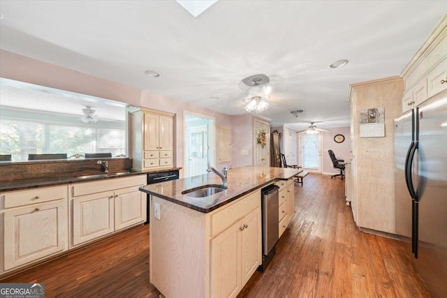 kitchen featuring wood finished floors, appliances with stainless steel finishes, a sink, and cream cabinetry