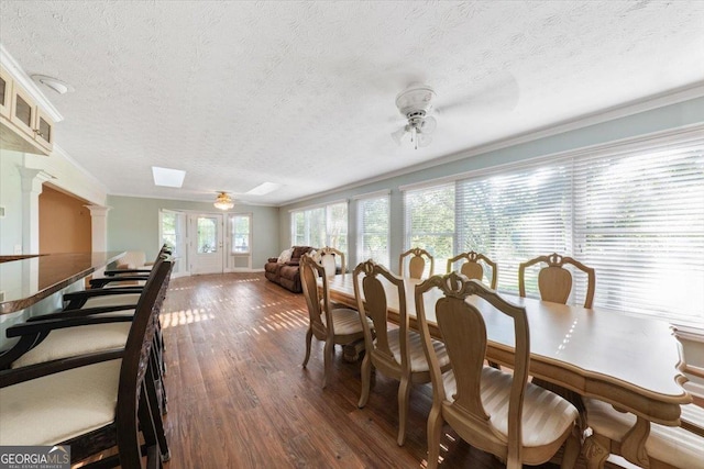 dining area featuring ornate columns, ceiling fan, a textured ceiling, and wood finished floors