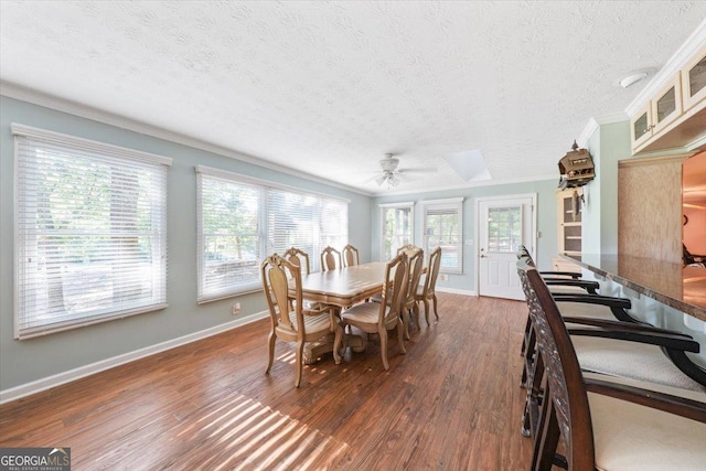 dining area featuring baseboards, plenty of natural light, ornamental molding, and wood finished floors