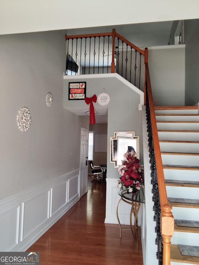 staircase with wainscoting, wood finished floors, and a decorative wall