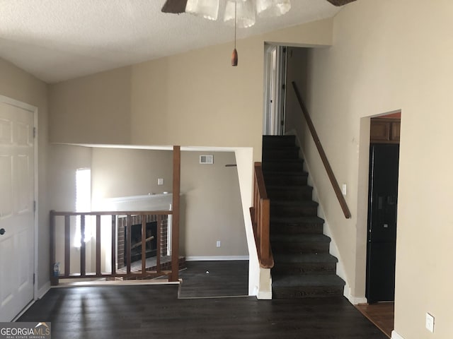 unfurnished living room with a fireplace, wood finished floors, a ceiling fan, visible vents, and baseboards