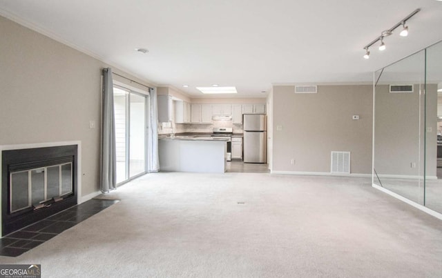 unfurnished living room featuring light carpet, a fireplace with flush hearth, and visible vents