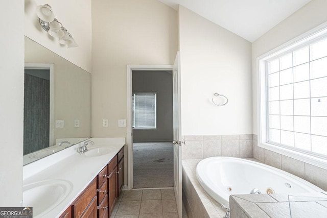 full bath with double vanity, tile patterned floors, a whirlpool tub, vaulted ceiling, and a sink