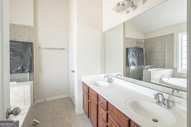 bathroom featuring tiled tub, double vanity, a sink, and tile patterned floors