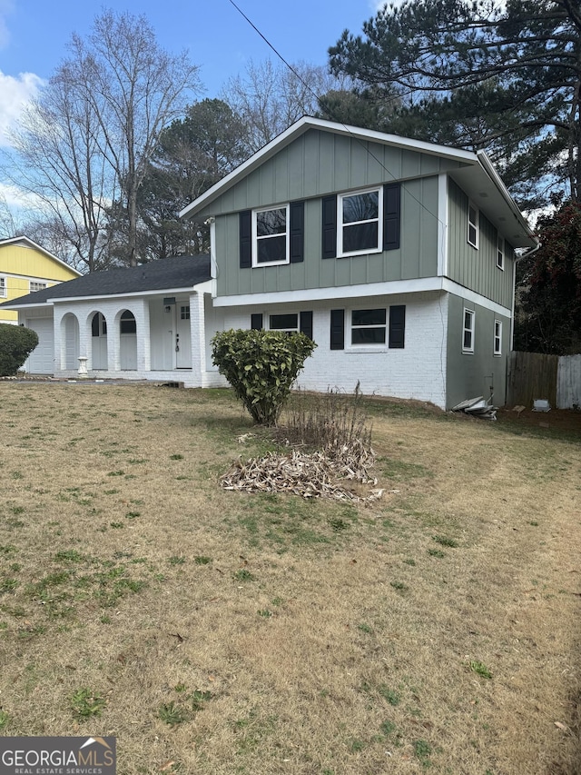 split level home with board and batten siding, brick siding, fence, and a front lawn