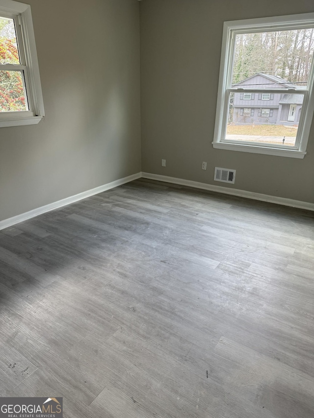 unfurnished room with visible vents, baseboards, and wood finished floors