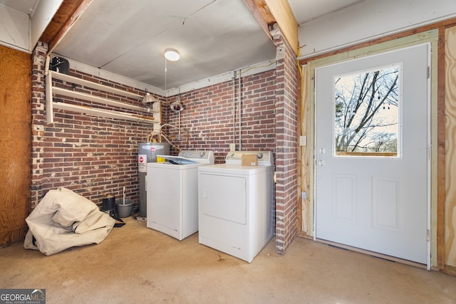 washroom with washing machine and dryer, laundry area, water heater, and brick wall