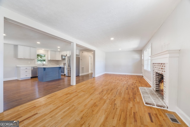 unfurnished living room with light wood finished floors, visible vents, and a wealth of natural light