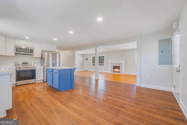 kitchen featuring electric panel, appliances with stainless steel finishes, blue cabinets, light countertops, and white cabinetry