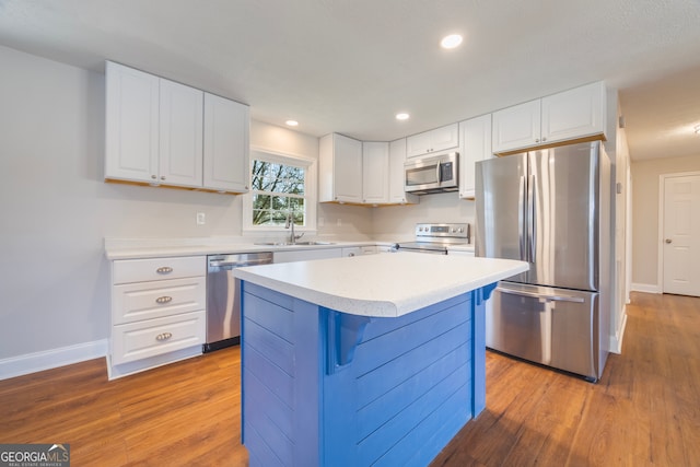 kitchen with recessed lighting, stainless steel appliances, wood finished floors, white cabinetry, and light countertops