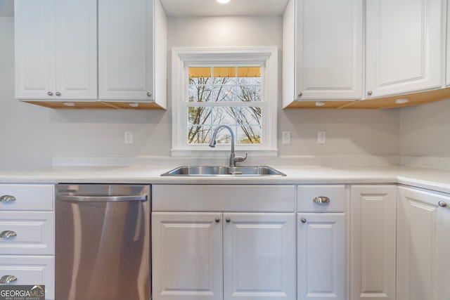 kitchen with dishwasher, light countertops, a sink, and white cabinetry