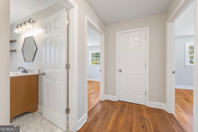 corridor with a healthy amount of sunlight, light wood finished floors, and baseboards