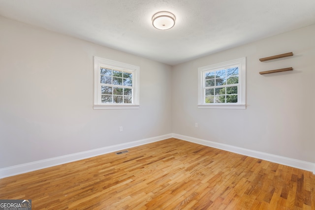 unfurnished room featuring a healthy amount of sunlight, baseboards, and visible vents