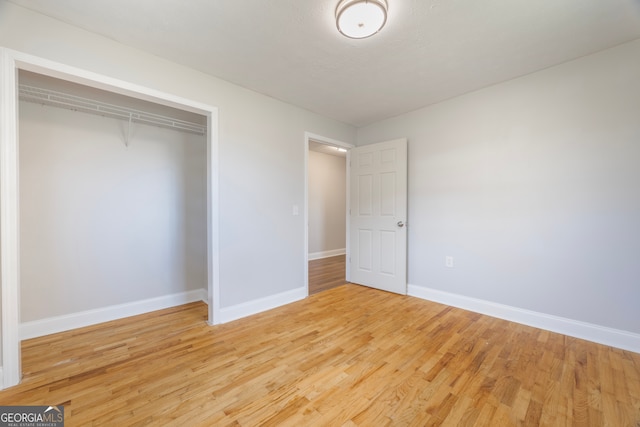 unfurnished bedroom with a closet, light wood-style flooring, and baseboards