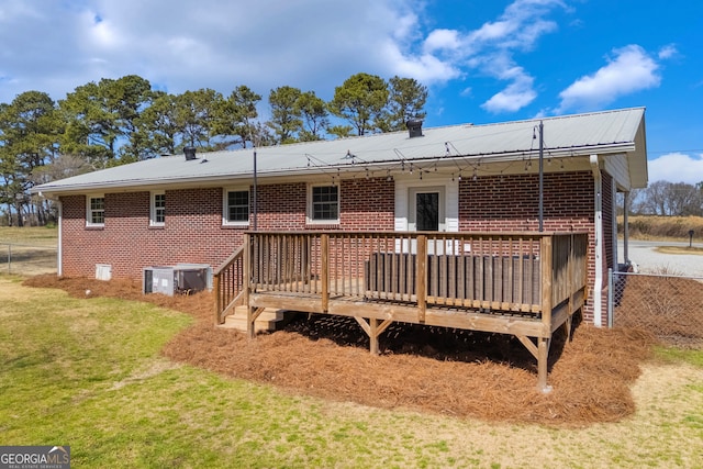 back of house featuring a yard, a wooden deck, metal roof, and brick siding