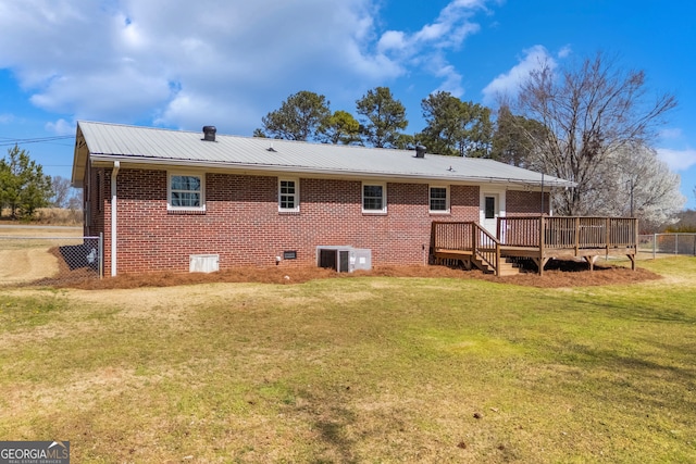 back of property with brick siding, a yard, metal roof, fence, and a wooden deck