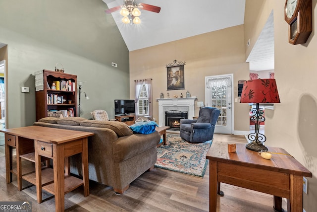 living room featuring visible vents, ceiling fan, a premium fireplace, wood finished floors, and high vaulted ceiling