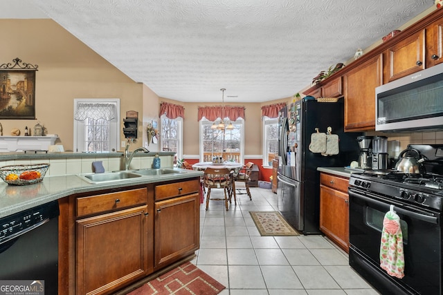 kitchen with decorative light fixtures, light tile patterned floors, brown cabinetry, a sink, and black appliances