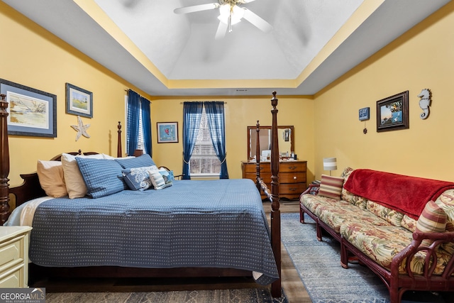 bedroom featuring a ceiling fan, a tray ceiling, and wood finished floors