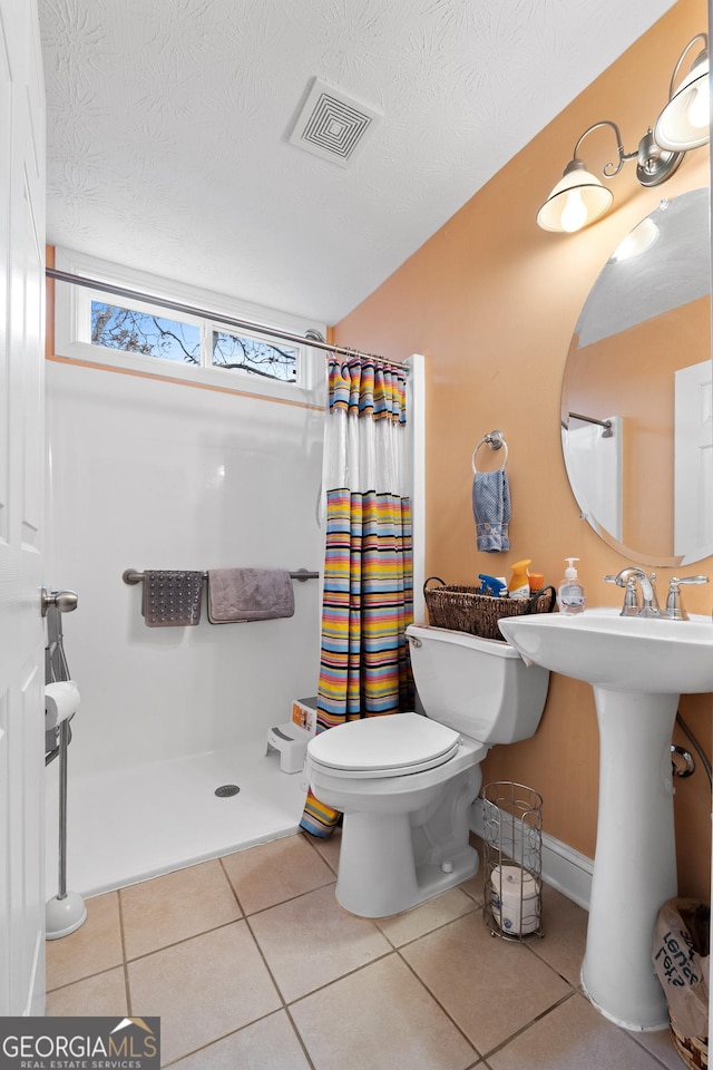 bathroom featuring a shower with curtain, visible vents, toilet, and tile patterned floors