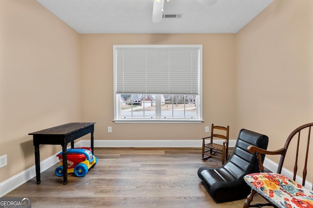 living area featuring visible vents, wood finished floors, a ceiling fan, and baseboards