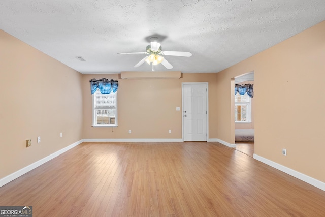 unfurnished living room with light wood finished floors, visible vents, ceiling fan, a textured ceiling, and baseboards