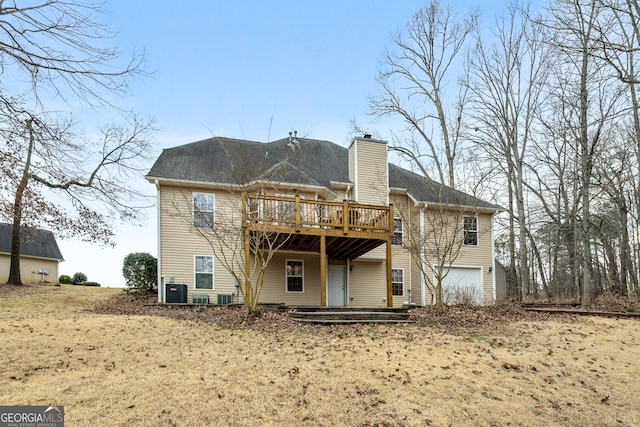 back of property with a garage, a chimney, a wooden deck, and central AC unit