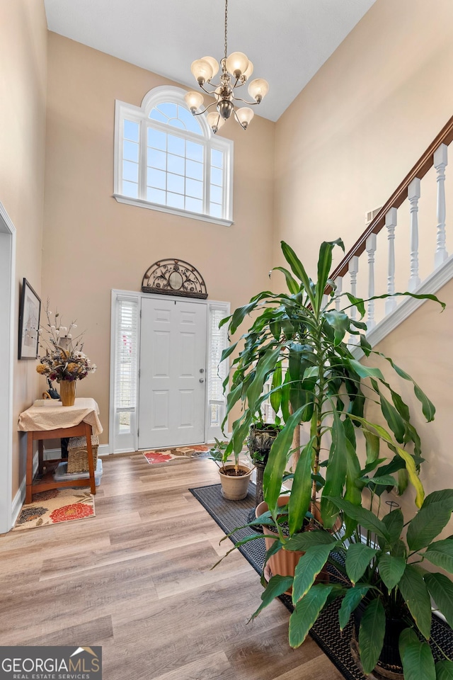 entrance foyer featuring a chandelier, a high ceiling, wood finished floors, and baseboards