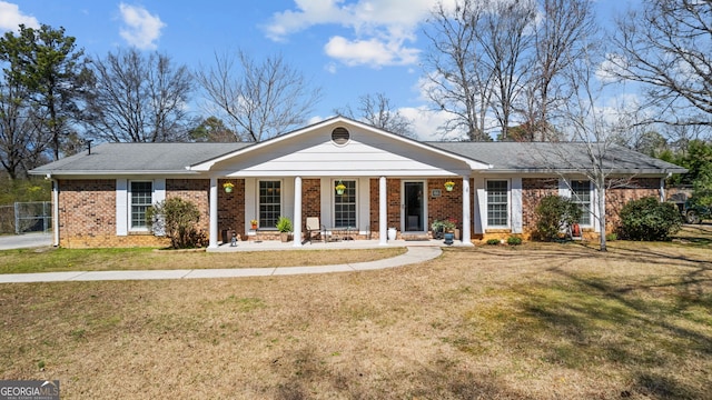 view of front facade with a front lawn, a porch, and brick siding